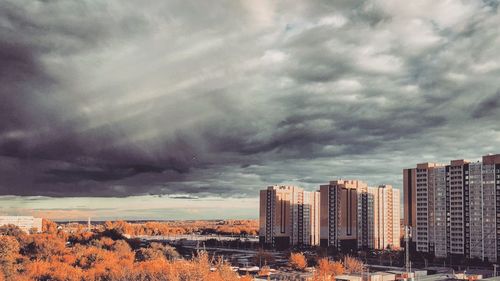 Buildings in city against dramatic sky