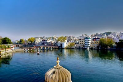 Cityscape by lake against clear sky