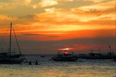 Sailboat sailing in sea at sunset