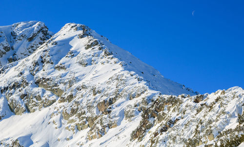Low angle view of snowcapped mountain against clear sky