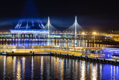 Illuminated bridge over river against sky in city at night