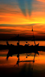 Silhouette boat in sea against orange sky