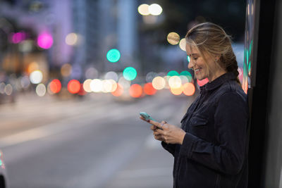 Woman with smartphone at night time on the street. mobile phone, technology, urban