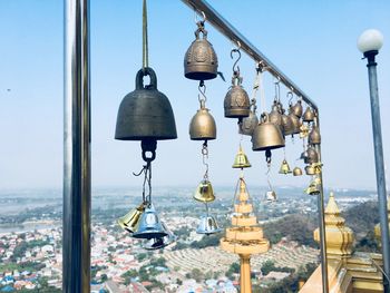Bells hanging on metal against clear sky