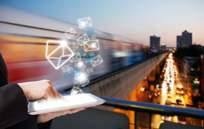 Person holding illuminated ferris wheel against sky in city