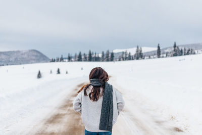 Rear view of woman standing on snow covered landscape