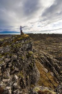 Person standing on rocky mountain against sky