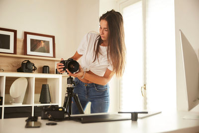 Woman photographing while standing on table at home