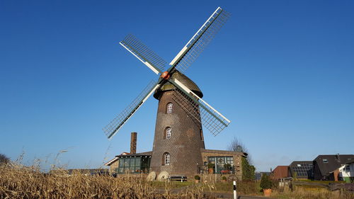 Traditional windmill on field against clear blue sky