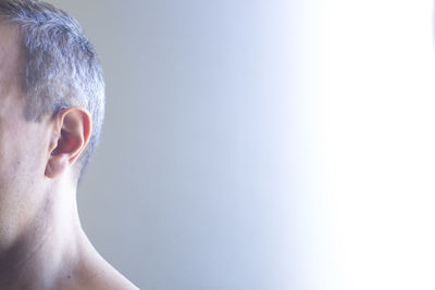 Close-up man wearing hearing aid against wall