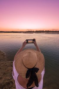 Rear view of man at riverbank during sunset