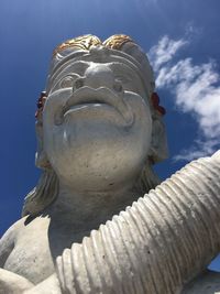 Low angle view of buddha statue against clear blue sky