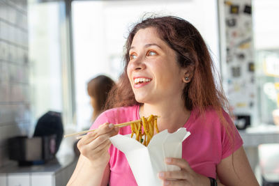 Smiling woman eating food at restaurant