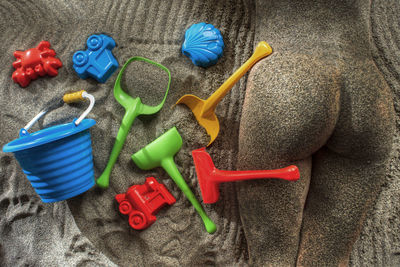 High angle view of naked woman lying by toy on sand