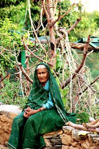 Portrait of smiling young woman sitting on tree