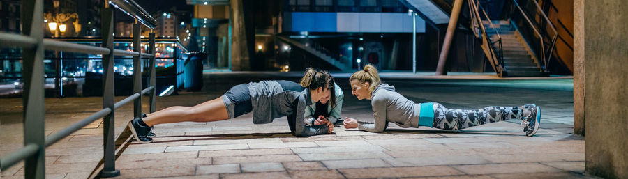 Women sport team doing plank exercise during training on the city at night