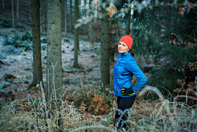 Portrait of smiling girl standing by trees in forest