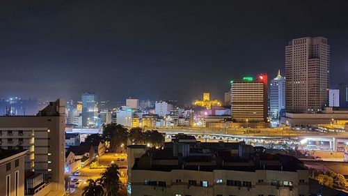 Illuminated buildings in city against sky at night