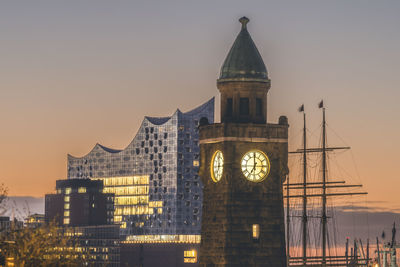 Germany, hamburg, pegelturm clock tower at dusk with elbphilharmonie in background