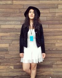 Portrait of smiling young woman standing against wood