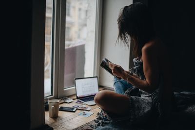 Woman reading book while sitting on floor at home