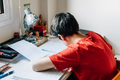 High angle view of teenage boy studying while sitting at home