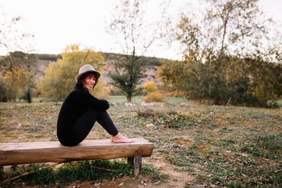 Side view of woman sitting on bench at park