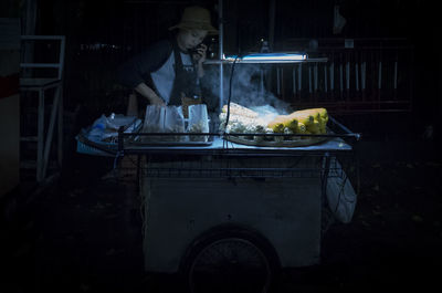 Woman talking on mobile phone while preparing food at market