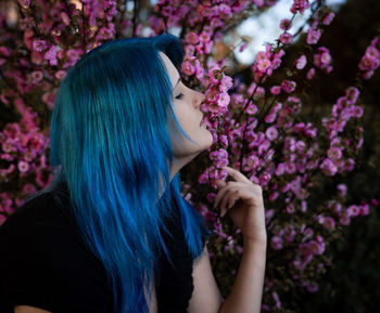 Dyed hair woman smelling flowers on plants at public park