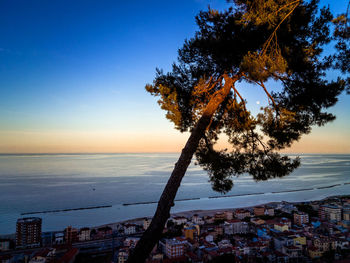 High angle view of cityscape by sea against sky during sunset