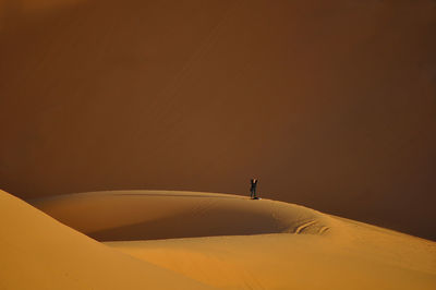 Silhouette person on sand dune against sky