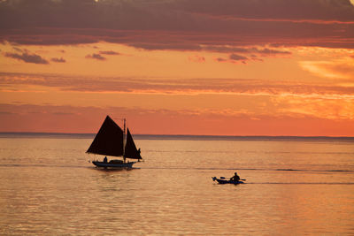 Silhouette boat sailing in calm sea at sunset