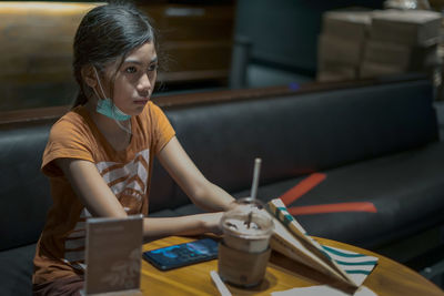 Girl looking away while sitting at cafe