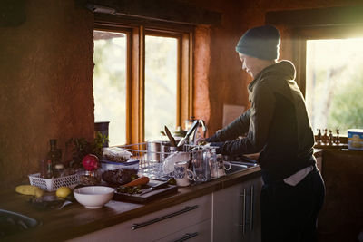 Side view of woman working in kitchen at home