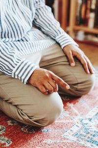 Midsection of woman sitting on bed at home