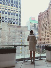 Rear view of woman standing against buildings in city