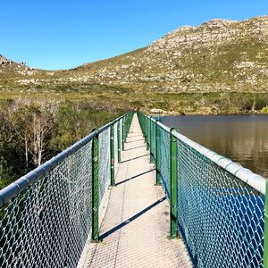 Footbridge over mountain against blue sky