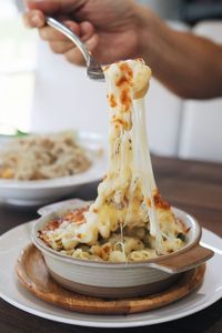 Cropped hand holding pasta with fork