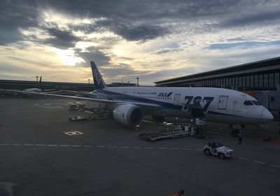 Airplane on airport runway against sky during sunset