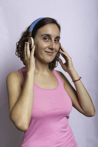 Portrait of smiling young woman standing against wall