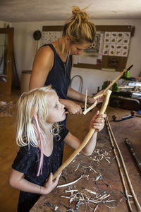 Mother and daughter in workshop working on stone-age spear-thrower