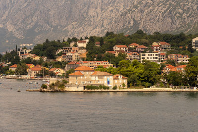 Buildings by sea against mountain