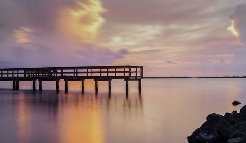 Pier on sea at sunset