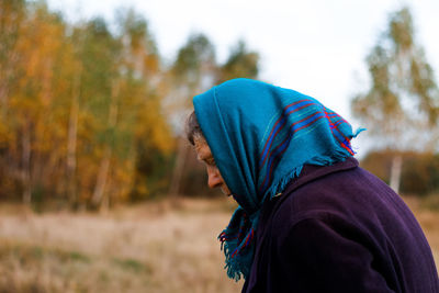 Portrait of russian grandmother senior old woman standing in yellow autumn park. old women in coat