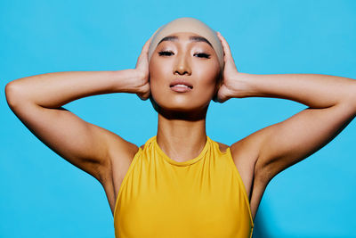 Portrait of young woman against blue background