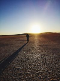 Woman walking on street against sky during sunset