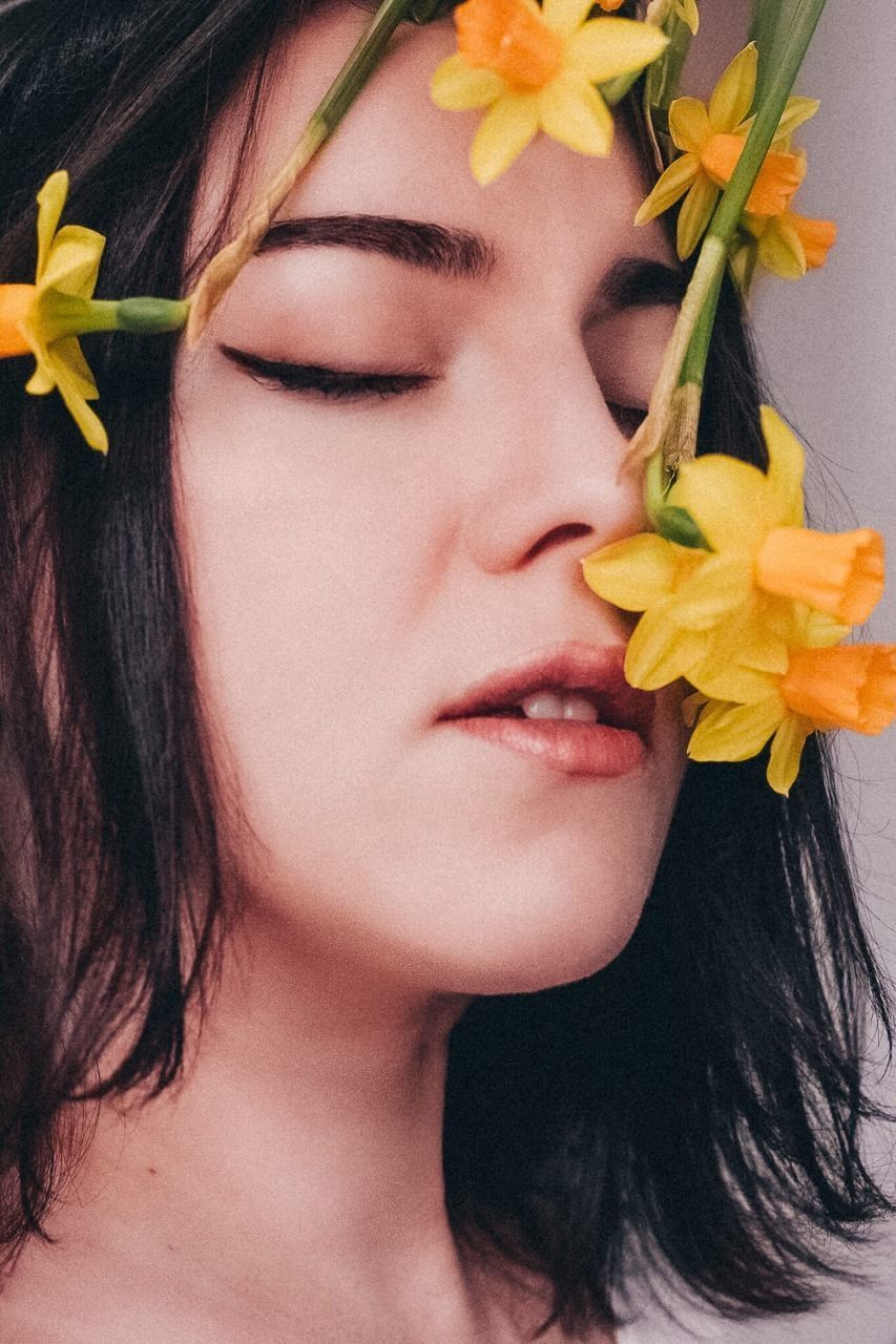 CLOSE-UP PORTRAIT OF BEAUTIFUL WOMAN WITH RED FLOWER