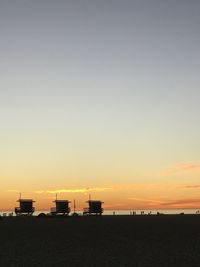 Scenic view of lifeguard huts by the sea against sky during sunset