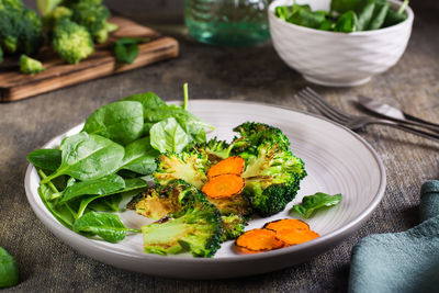 Fried broccoli, carrots and spinach leaves on a plate. healthy food.