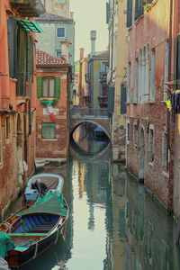 Boats moored in canal amidst buildings in city